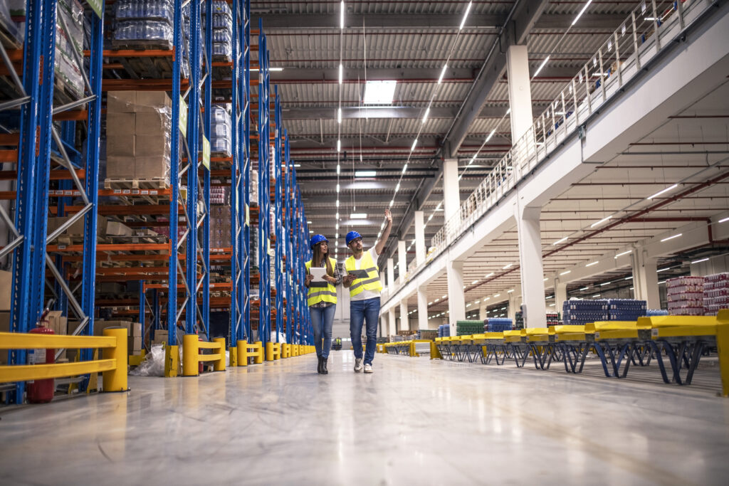distribution warehouse interior with workers wearing hardhats reflective jackets walking storage area