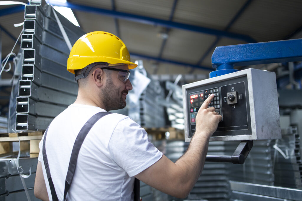 factory worker operating industrial machine setting parameters computer